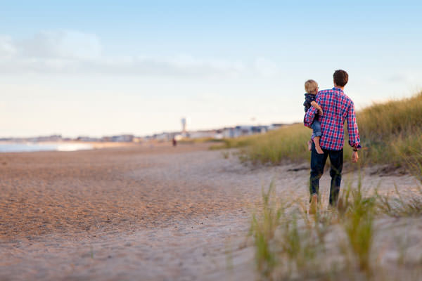 Vater mit Kind auf dem Arm am Strand