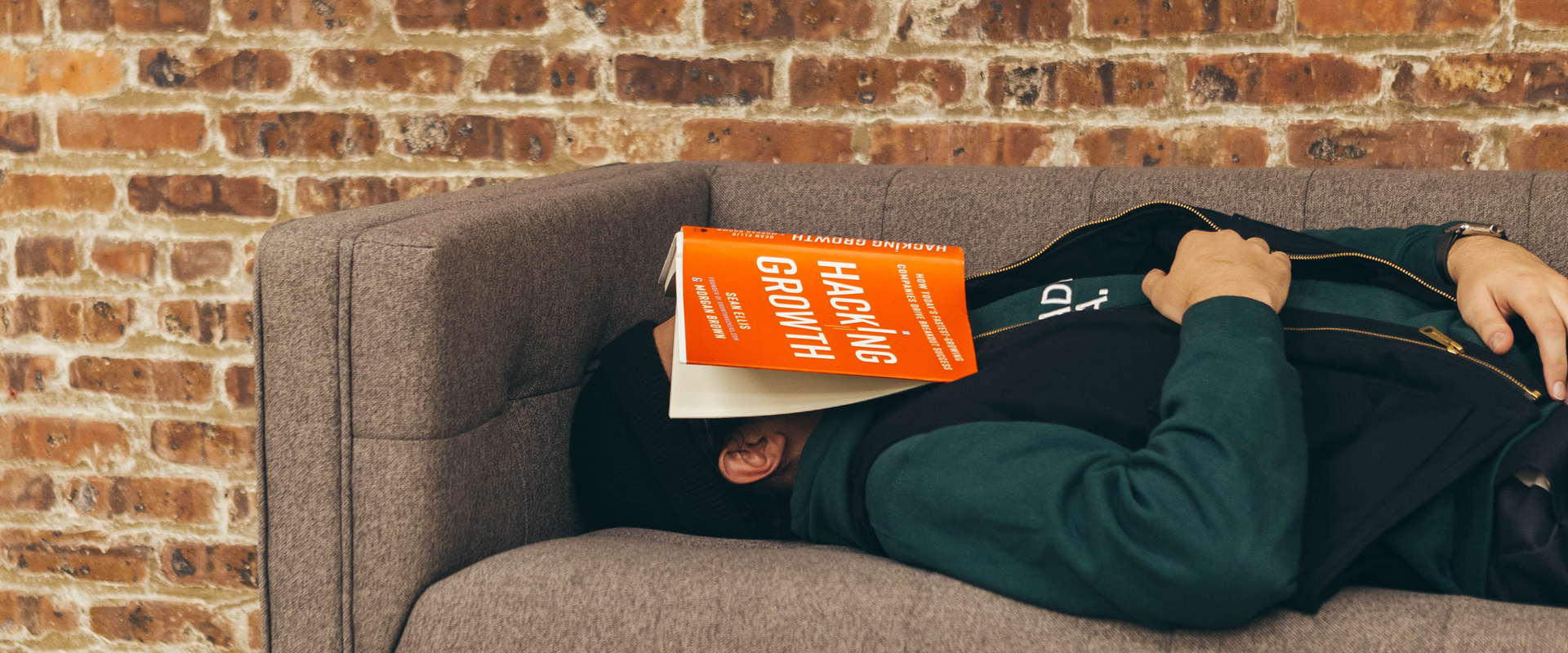 Mann schläft auf einem Sofa mit einem Buch auf seinem Gesicht.