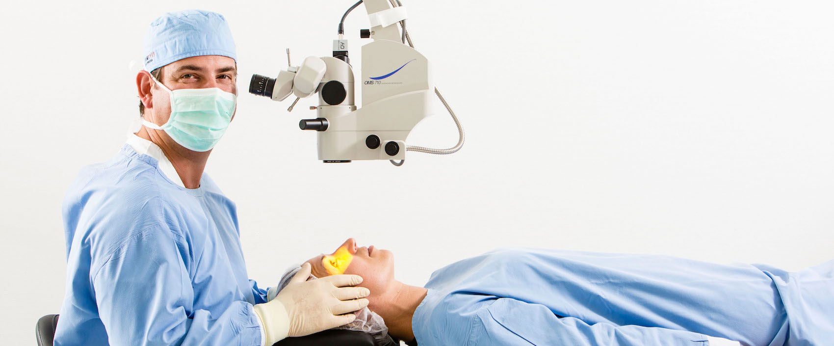 Dr. Detlev Breyer als Operateur am Mikroskop, auf der Liege vor ihm ist eine Patientin.