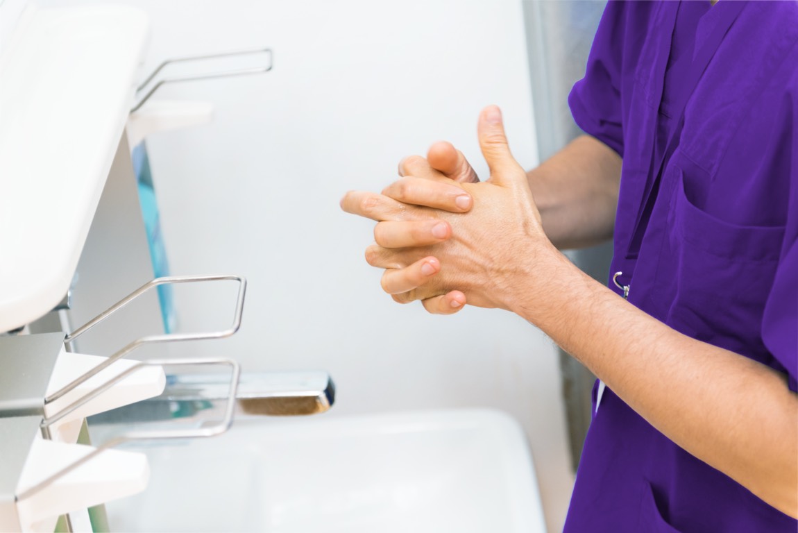 Ärztlicher Mitarbeiter bei einer hygienischen Händedesinfektion am Waschbecken.